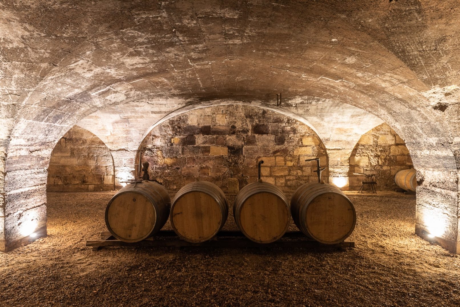 cave voutée et éclairée avec des tonneaux de vin