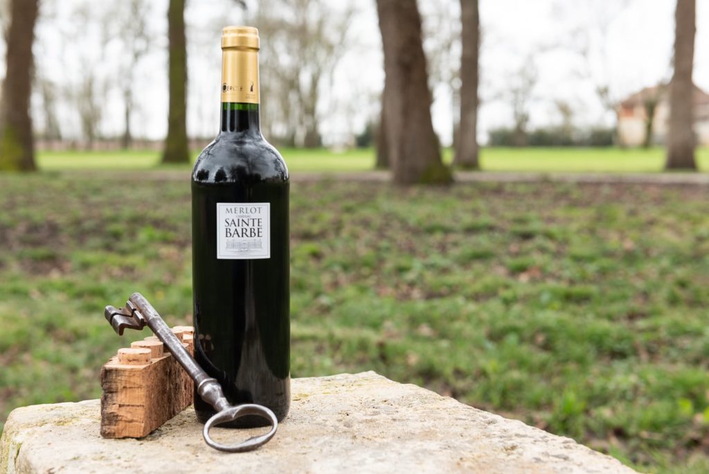 bouteille de vin rouge présentée dans un parc avec une clé et du liège