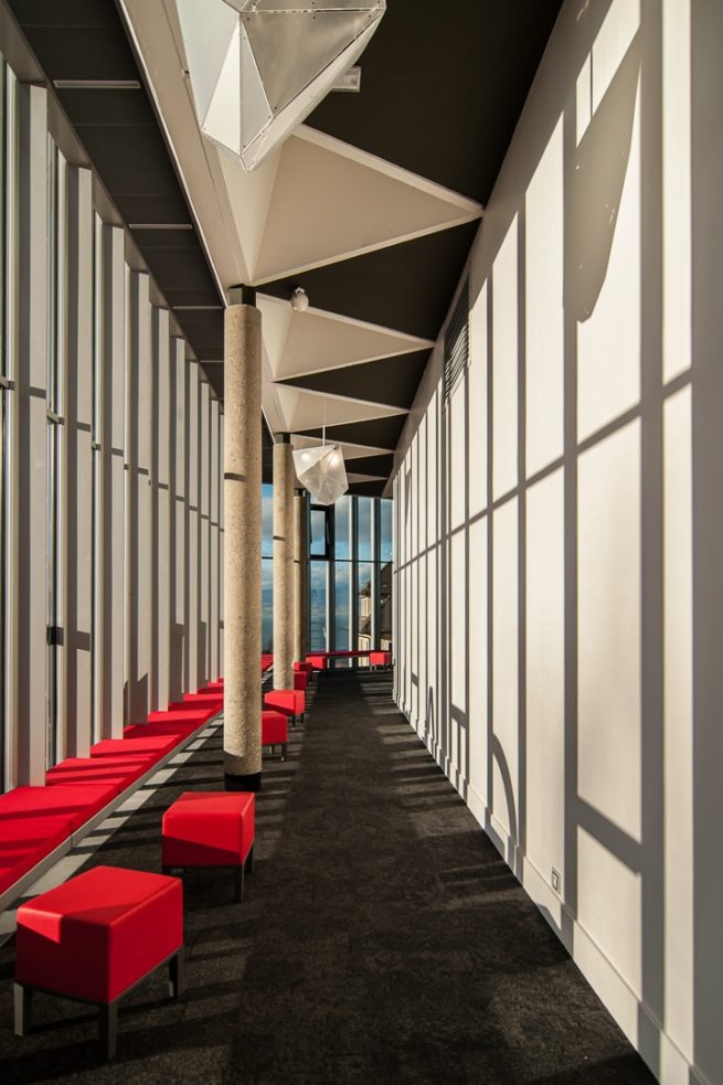 Interieur du batiment avec du mobilier rouge, des jeux de lumiere