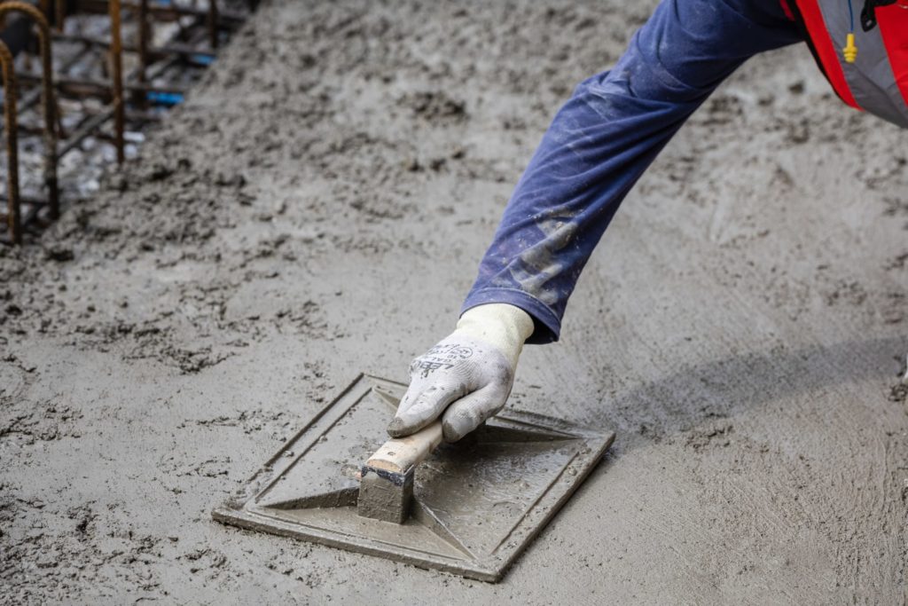un maçon taloche du béton frais