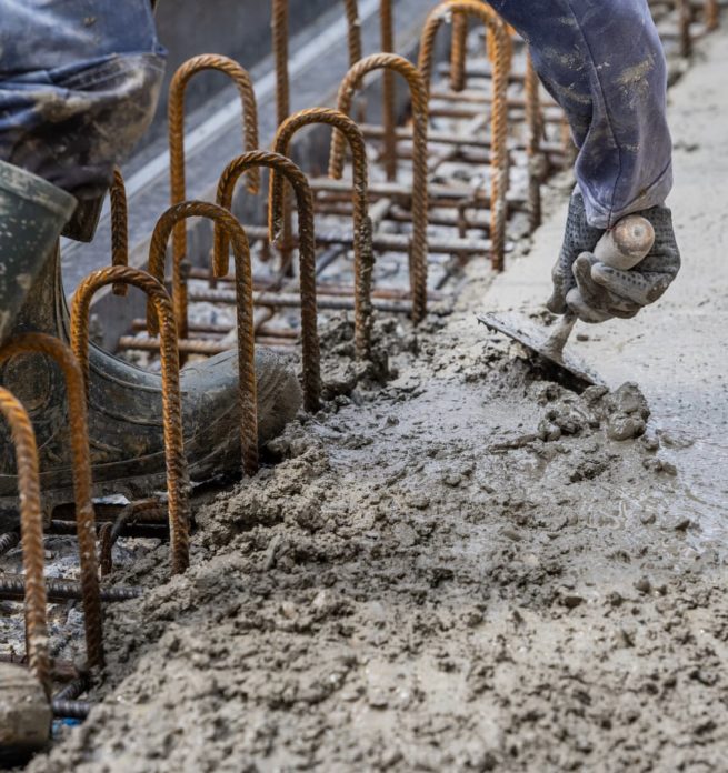 un maçon réalise des finitions sur du béton frais avec une truelle
