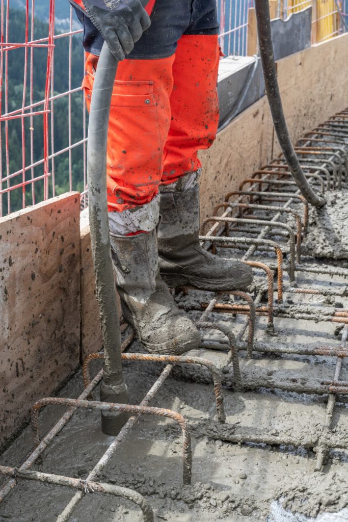un maçon vibre le béton avec une aiguille vibrante